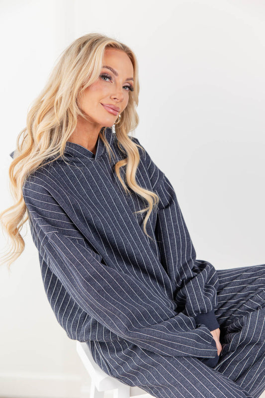 A woman wearing a navy blue and white pinstriped hoodie lounge set.