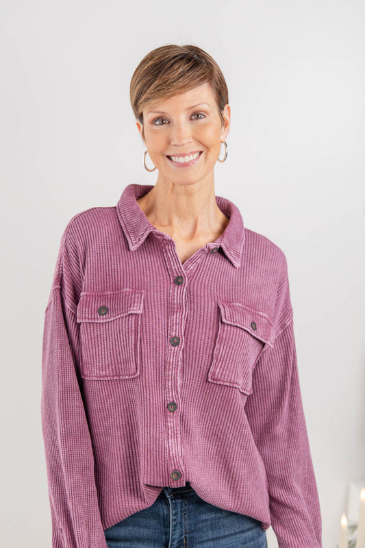 A woman wearing a purple textured waffle knit button-up long sleeve top.
