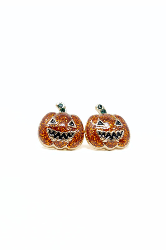 A pair of pumpkin-shaped stud earrings with orange glitter enamel, carved jack-o'-lantern faces, and small green stems, shown on a plain white background.