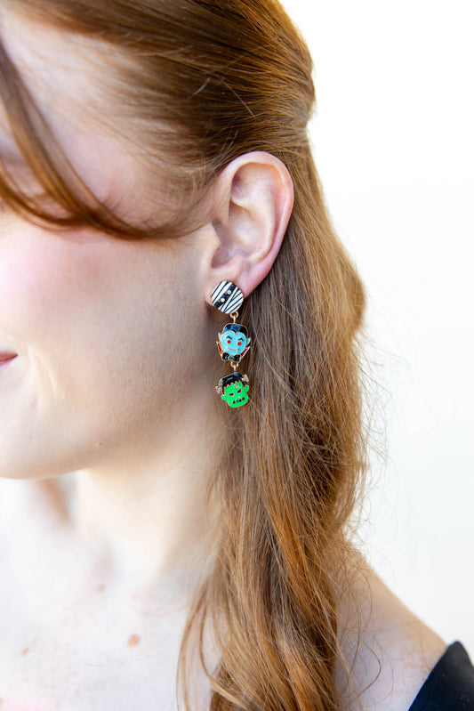 Close-up of a person wearing colorful halloween characters earrings with a blurred background