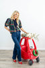 A woman stands wearing a navy, green and red plaid short-sleeve knit blouse with dark blue trim, blue jeans, and red heels.