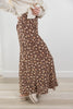 A person wearing a brown floral maxi skirt with a cream knit sweater and cream platform shoes, standing in a bright indoor room with light wood flooring.