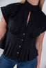 A close-up of a woman wearing a black short-sleeve blouse with a high mock neck, front keyhole cutout, gathered waist, and button-front peplum hem, paired with blue jeans.
