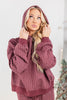 A woman wearing a cozy maroon hooded sweatshirt and matching pants with thin white vertical pinstripes.