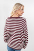 A woman wearing a maroon and white horizontally striped knit sweater, shown from a three-quarter back view against a plain white studio background.