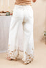 White wide-leg jeans with gold embroidered floral patterns along the hem, shown from the back on a woman.