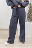 A woman wearing navy wide-leg pinstripe  lounge pants with a drawstring waist and side hip pockets.