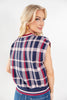 A woman wearing a sleeveless knit top with a navy, white, and red plaid pattern, shown from a back-three-quarter view against a plain white background.