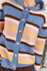 A close-up of a fuzzy knit cardigan with horizontal stripes in blue, brown, cream, yellow, and pink, featuring a blue ribbed button placket and tortoise buttons.