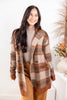 A woman wearing a brown and beige plaid knit cardigan over a taupe turtleneck and brown pants.