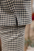 Close-up of a black and beige gingham checkered fabric garment, showing the texture and a small central seam or slit.