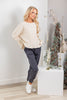 A woman modeling a long sleeve crew neck cream-colored knit top and dark gray pants.