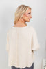 A woman shown from the back wearing a cream-colored, waffle knit top with a back seam detail.