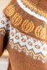 Close-up of a knit sweater featuring a brown base with orange pumpkin motifs and white geometric patterns, including a white border with green accents.