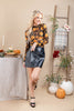 A woman models a long-sleeve black top with a yellow and orange floral pattern, paired with a black faux-leather mini skirt and black high-heeled sandals, in a styled autumn-themed room setting.