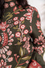 Close-up of a woman wearing a dark olive green knit sweater with a pink, red, and light green floral pattern.