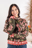 A woman wearing a dark olive green long-sleeve sweatshirt with a red and pink floral pattern and a scalloped red hem, paired with blue jeans.