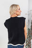 A woman shown from the back wearing a sleeveless black ribbed knit sweater vest with a white trim.