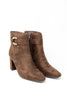 A pair of brown suede ankle boots with pointed toes, block heels, and a gold-tone buckle detail on the side, shown against a plain white background.