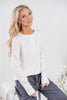 A woman wearing a white long-sleeve henley shirt and dark gray drawstring pants.
