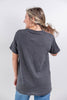 A woman shown from the back wearing a dark heather gray short-sleeve t-shirt and blue jeans, standing against a light gray studio background.