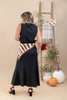 A woman stands with her back to the camera wearing a sleeveless black midi dress with a brown and white zebra-patterned scarf. She is posed in a studio setting with a wooden ladder, pumpkins, and floral decor against a beige background.