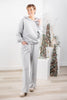 A woman modeling a light gray two-piece loungewear set consisting of a hooded sweatshirt and matching wide-leg pants.