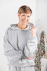 A woman wearing a gray hooded sweatshirt and matching pants with thin white vertical pinstripes.