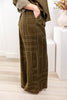 A woman wearing wide-leg olive green trousers with a beige geometric line pattern.