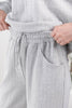Close-up of a woman wearing light gray heathered lounge pants with a drawstring waist and a side pocket, paired with a matching top.