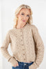 A blonde woman wearing a beige pointelle cable-knit button-up cardigan sweater with blue jeans, photographed against a clean white studio background.