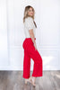 A woman modeling bright red wide-leg cropped pants with a cream puff-sleeve top.