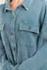 Close-up of a woman wearing a blue waffle knit button-up shirt with chest flap pockets and dark buttons.