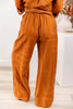 A woman wearing wide-leg orange trousers with a white geometric line pattern.