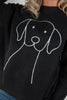 A close-up of a black knit sweater featuring a white line-art graphic of a dog face on the front, worn by a woman.