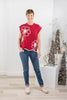 A woman modeling a red sleeveless knit top with large white floral motifs.