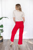 A woman shown from behind wearing bright red straight-leg pants, a beige short-sleeve top, and beige heels.