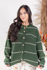 A woman wearing a dark green knit cardigan sweater with thin horizontal cream stripes and button front.