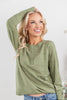 Woman wearing a sage green textured stripe long-sleeve henley top with a button placket.