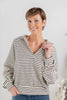 A woman modeling a cream and black horizontally striped long-sleeve top with a split V-neck.