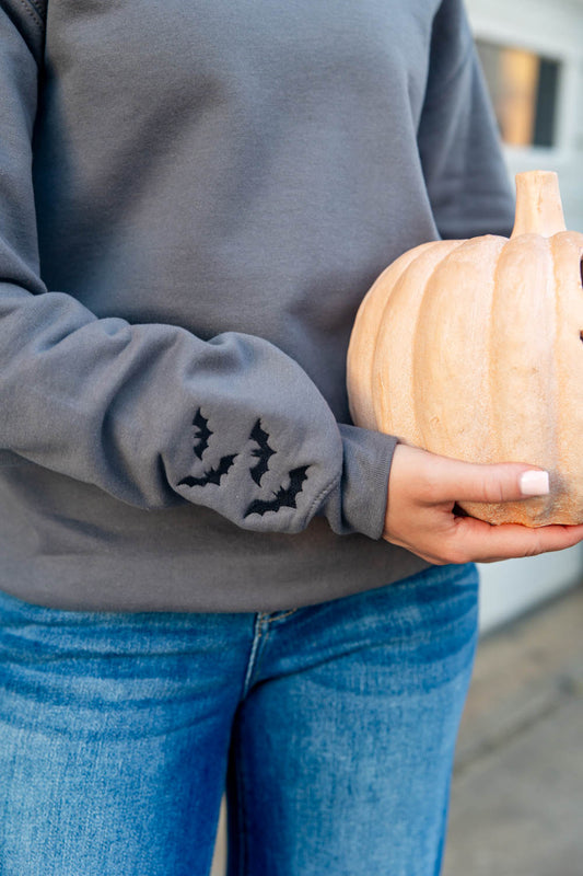 Close up of embroidered bats along sleeves of gray sweatshirt