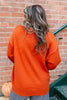Woman from behind wearing an orange knit sweater