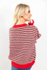 A woman shown from the back wearing a red, green, and white patterned knit sweater with red ribbed collar, cuffs, and hem, paired with blue jeans.