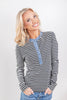 A woman wearing a long-sleeve henley top with black and white horizontal stripes and a light blue denim-style placket and collar.
