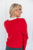 A woman with blonde hair is shown from the back wearing a bright red knit sweater over a white top.