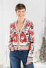 A woman wearing a cream-colored cardigan with a vibrant red and black floral pattern and gold buttons.