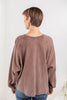 A woman shown from the back wearing a brown waffle knit long-sleeve top.