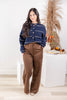A woman modeling a navy blue cropped knit cardigan with cream stripes and brown wide-leg pants.