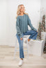A woman wearing a dusty teal long-sleeve crewneck waffle knit top.