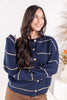 A woman wearing a navy blue knit cardigan sweater with beige stripes and button front.